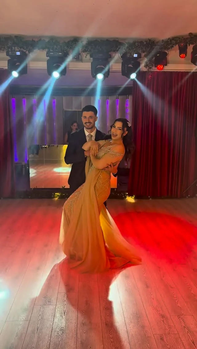 Turuncu elbiseli nişan çiftinin renkli sahne ışıklarında dansı